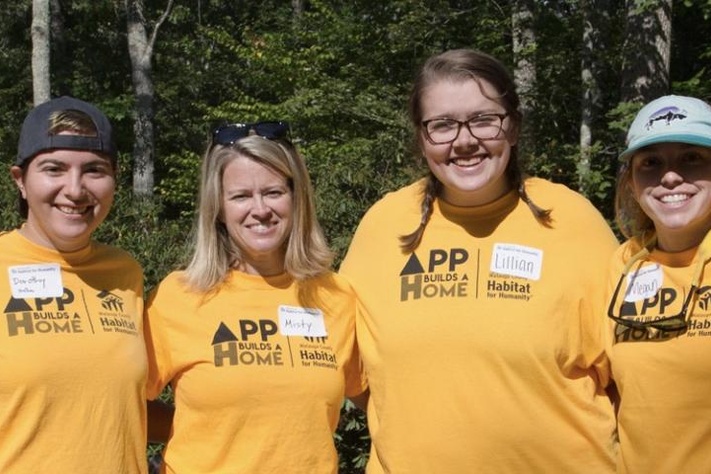 6 App Builds a Home volunteers in yellow ABAH t-shirts. 