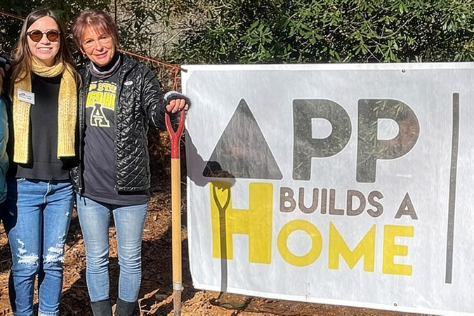 App Builds a Home volunteers in front of App Builds a Home and Habitat for Humanity banner.